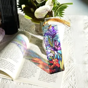 Detailed close-up of colorful stained glass acrylic bookmark with golden tassel on open book.