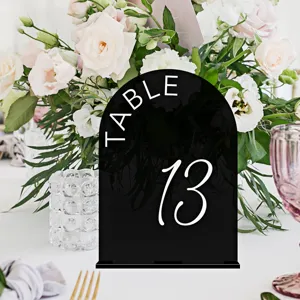 Black acrylic arch table number sign with white text for wedding party table decoration detail view.