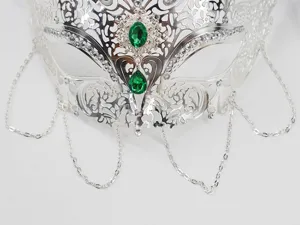 Primo piano dettagliato della maschera di carnevale argentata con strass e pietre verdi.