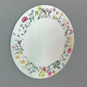 Espejo acrílico decorativo ovalado con un diseño de corona floral colorida.