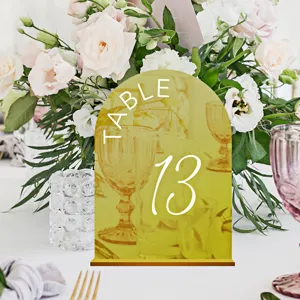 Gold acrylic arch table number sign for wedding reception decor, elegant display piece.
