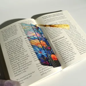 Colorful transparent acrylic bookmark with golden tassel, elegant floral detail close-up shot.