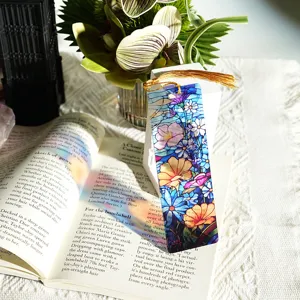 Close-up view of a colorful translucent acrylic bookmark with golden tassel on open book page.