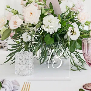 Close-up detail of clear acrylic arch table number sign decorated with elegant wedding floral setup.