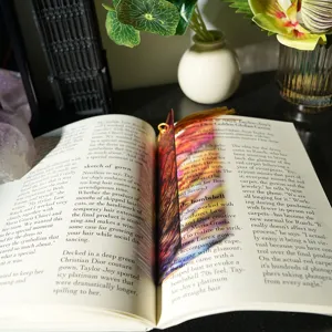 Detailed view of a creative colorful translucent acrylic bookmark with a tassel placed in a book.