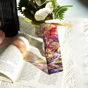 Detailed view of colorful translucent acrylic bookmark with gold tassel and artistic tree design.