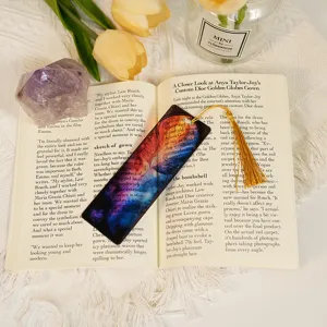 Close-up of translucent acrylic bookmark with colorful dragon pattern and gold tassel.