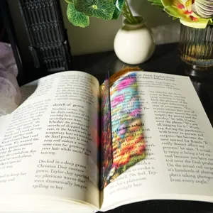 Detail view of a colorful translucent acrylic bookmark with tassel, showing light refraction.