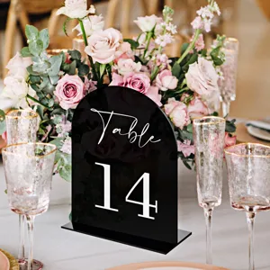 Black acrylic table number sign detail view with elegant floral background for wedding decor.