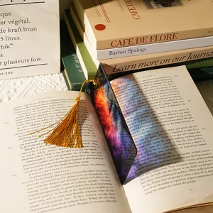 Detailed shot of a colorful translucent acrylic bookmark with a golden tassel, placed in a book.