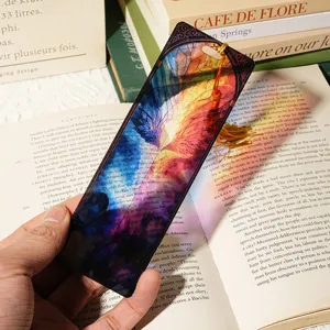 Close-up detail of translucent acrylic bookmark with colorful wing design and gold tassel.