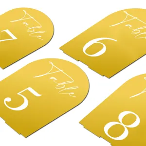 Close-up detail of gold arched acrylic wedding table number cards with crisp white text display.
