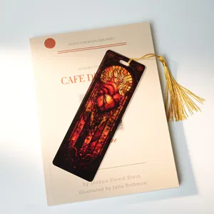 Stained glass anatomical heart acrylic bookmark detail with elegant gold tassel placed on book.