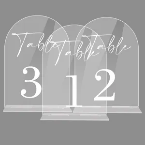 Close-up detail of transparent acrylic arch table number signs with bases for wedding decor.