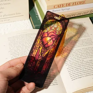 Close-up of stained glass style anatomical heart acrylic bookmark with golden tassel detail.
