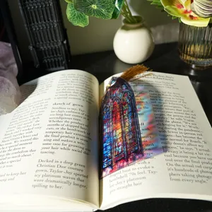 Detailed shot of a stained glass translucent acrylic bookmark with tassel placed on an open book.