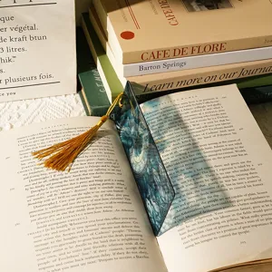Close-up detail view of the translucent acrylic dragon pattern bookmark with gold tassel.