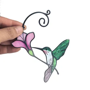 Close-up of metal hummingbird hanging ornament with vibrant stained glass wings and flower.
