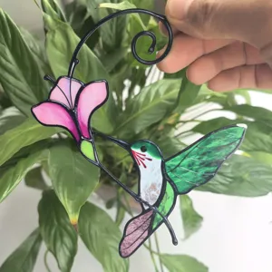 Detail shot of metal hummingbird and flower window hanging ornament, beautiful stained glass craft.