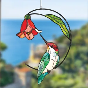 Stained glass style hummingbird and red flower metal hanging ornament detail shot for window.