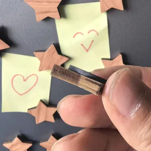 Close-up detail shot of wooden magnetic fridge sticker showing thickness and backing.