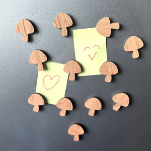 Detail shot of wooden mushroom fridge magnets holding sticky notes on metal surface.