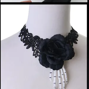 Detail van zwarte kanten goth choker halsketting met donkere roos en skeleton hand.
