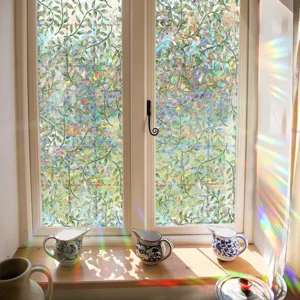 Detail shot of iridescent window film showing vibrant rainbow prism light effects and leaf pattern.