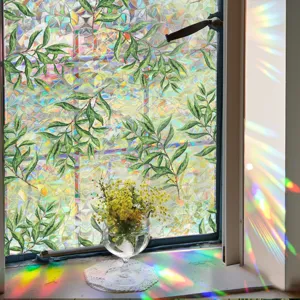 Prismatic window film detail showing vibrant rainbow light refraction and realistic green leaf patterns.