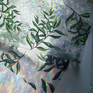 Close-up of decorative window film featuring vibrant green leaves and rainbow prism light effect.