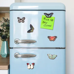 Close-up view of decorative wooden butterfly fridge magnets displayed on a retro blue fridge.