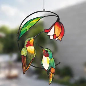 Close-up of metal iron stained glass hummingbird window hanging decoration with flower and leaf.