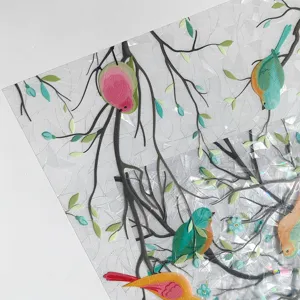 Close-up of colorful iridescent window glass film showcasing bird and branch decorative details.