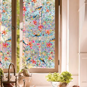 Close-up detail of colorful prism window film featuring floral and bird pattern with rainbow effect.