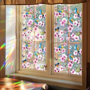 Decorative window film with blue birds and cherry blossoms creating rainbow prism light effects.