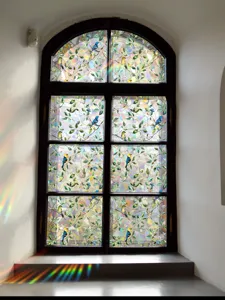 Stained glass window film with colorful birds and leaves, casting beautiful rainbow light.
