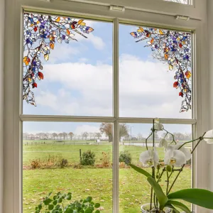Detailed view of colorful stained glass window film featuring tree branch design for home decor.