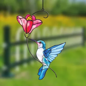 Detailed close-up of a colorful metal hummingbird and flower window hanging ornament.