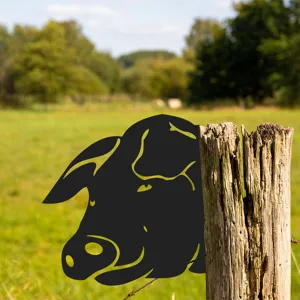 Detail shot of black metal pig silhouette garden stake peeking behind a wooden fence post in grass.