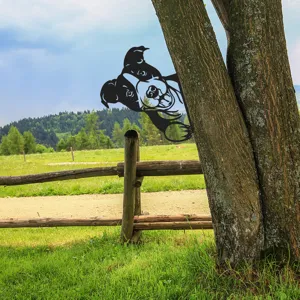 Outdoor metal dog garden art detail showing peek a boo puppy silhouette on tree trunk decor.