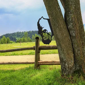 Metal bigfoot silhouette garden tree stake detail showing black iron finish outdoors.