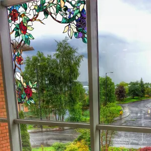 Static cling stained glass window film with floral plant design for privacy and home decor.