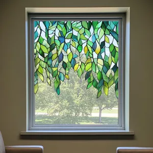 Detailed view of decorative stained glass window film featuring green leaves design for privacy.