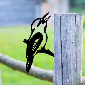 Detail view of a black metal woodpecker silhouette garden stake mounted on a wooden fence.