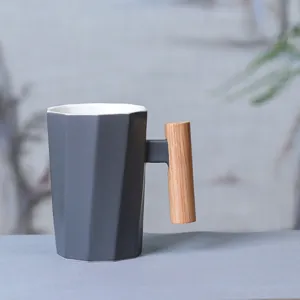 Modern ceramic coffee mug with unique wooden handle, geometric faceted grey cup body for office.