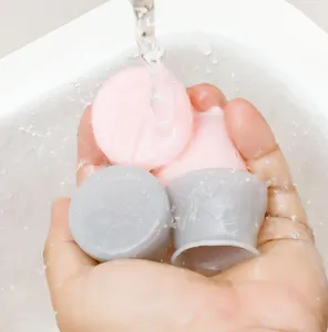 Detail shot of washable silicone chair leg caps in pink and gray, showing waterproof and non-slip design.