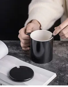 Ceramic coffee mug detail shot, classic black and white design with matching lid and spoon.