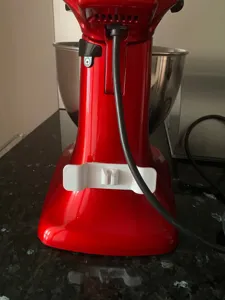Vista dettagliata di un organizer per cavi adesivo bianco fissato al mixer da cucina.
