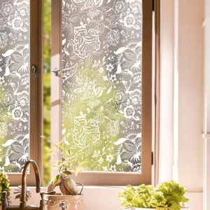 Detail view of white lace floral static window glass sticker showing frosted texture in light.