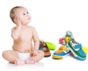 Detailed view of cute baby shoes and toys with a smiling infant in a clean studio setting.
